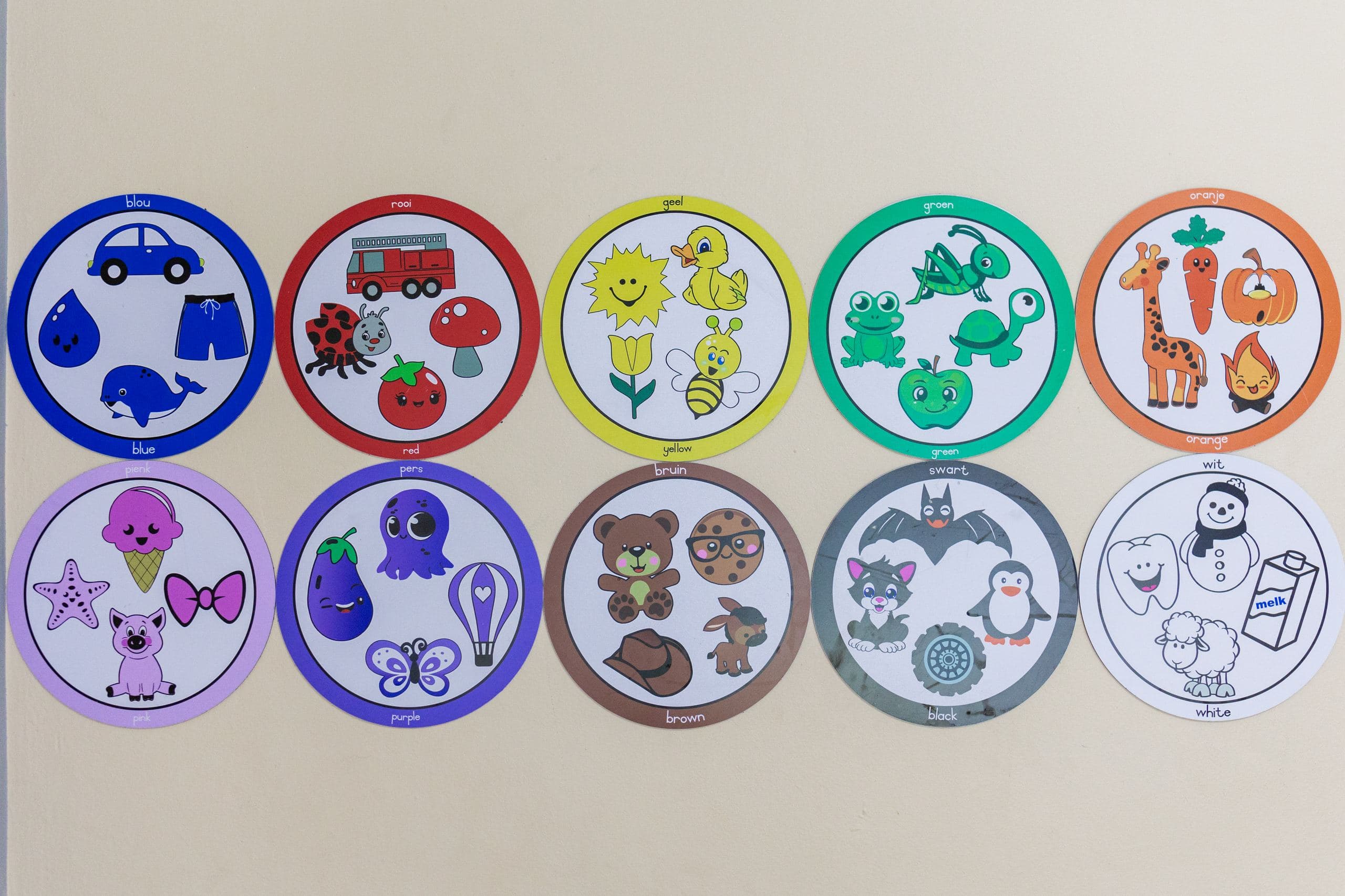 Bilingual colour-and-object learning posters on the wall above cots in the baby room