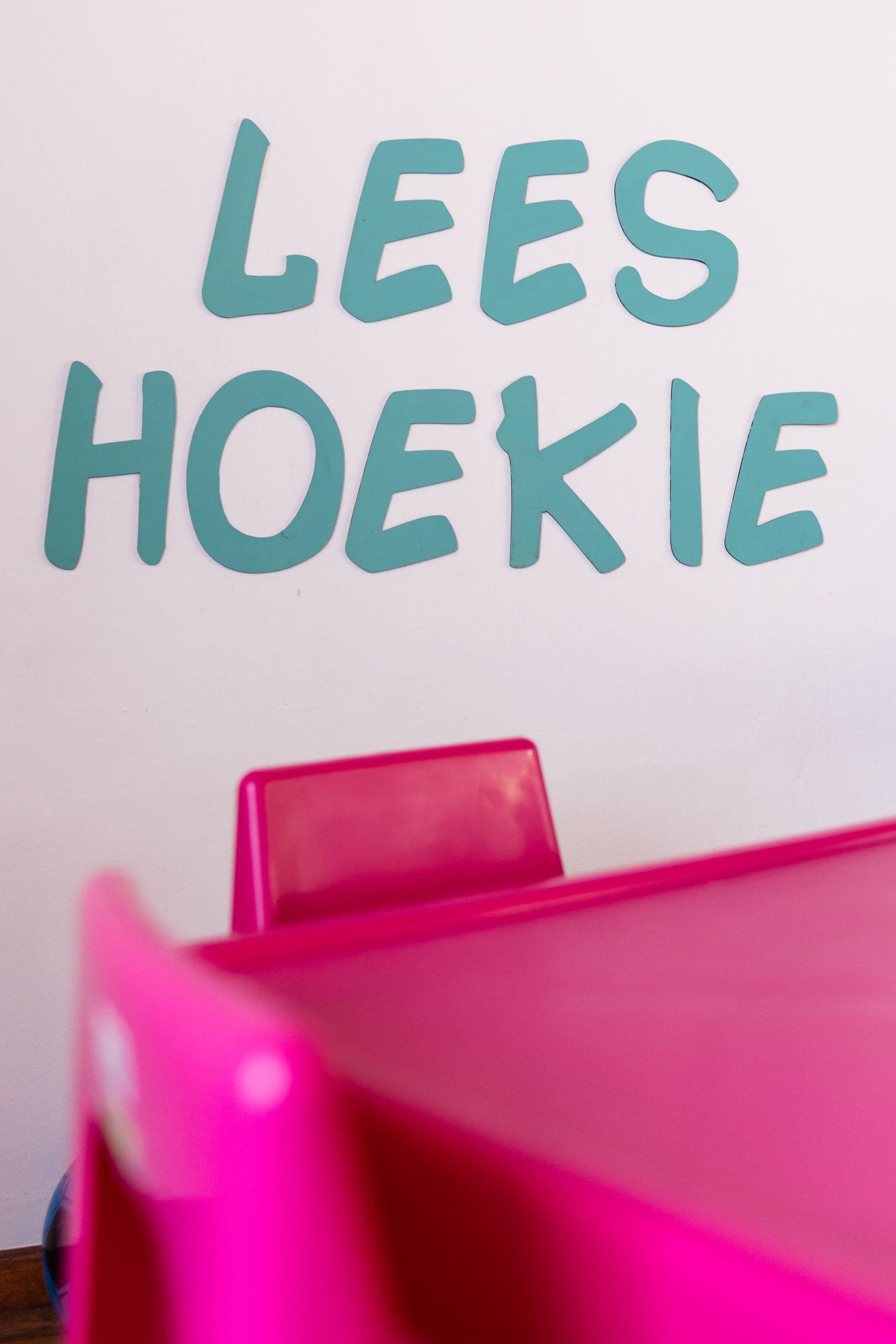Close-up of the ‘Lees Hoekie’ (reading corner) wall lettering above a children's chair